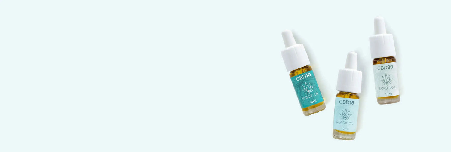 Tre flaskor med CBD-olja ligger på en blå bakgrund.