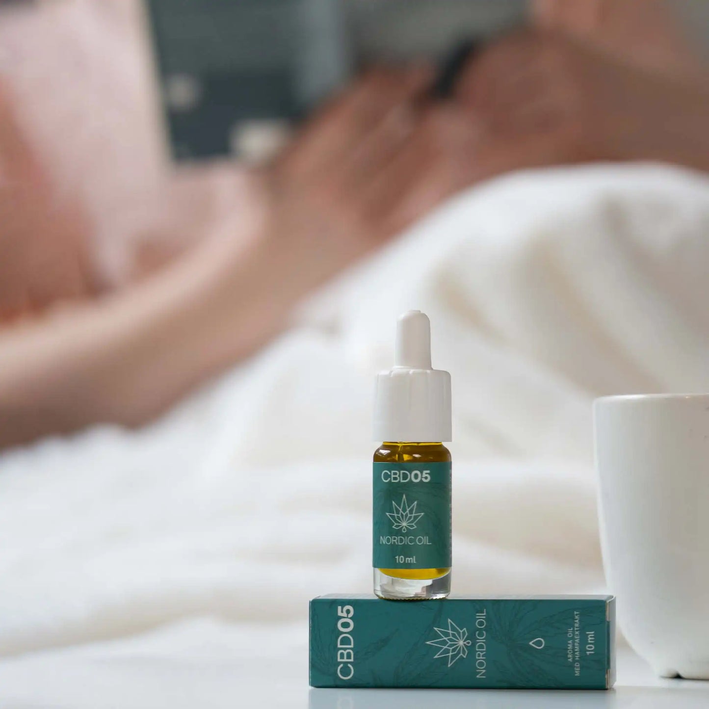 En flaska CBD Aroma Oil 5 % ovanpå sin förpackning.