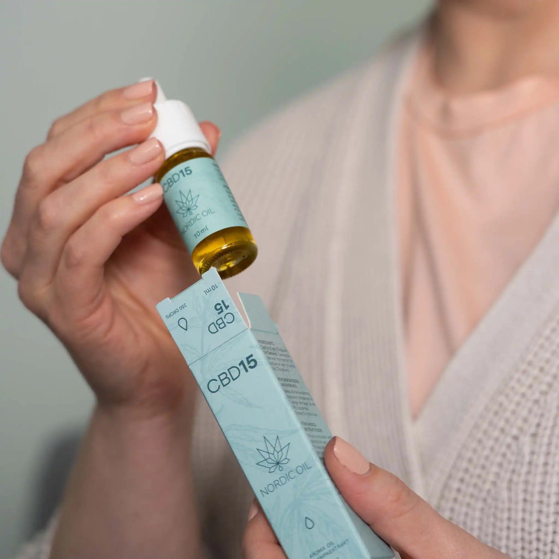 Kvinna som tar ut en flaska CBD-aroma oil 15 % från sin förpackning.