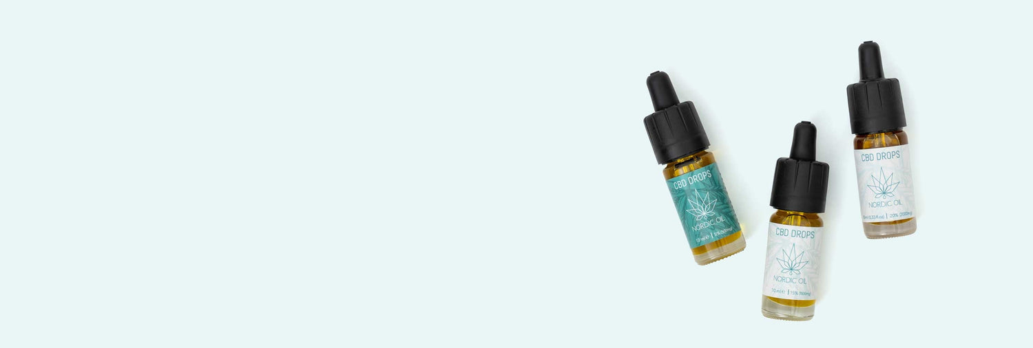 Tre flaskor med CBD-olja ligger på en blå bakgrund.